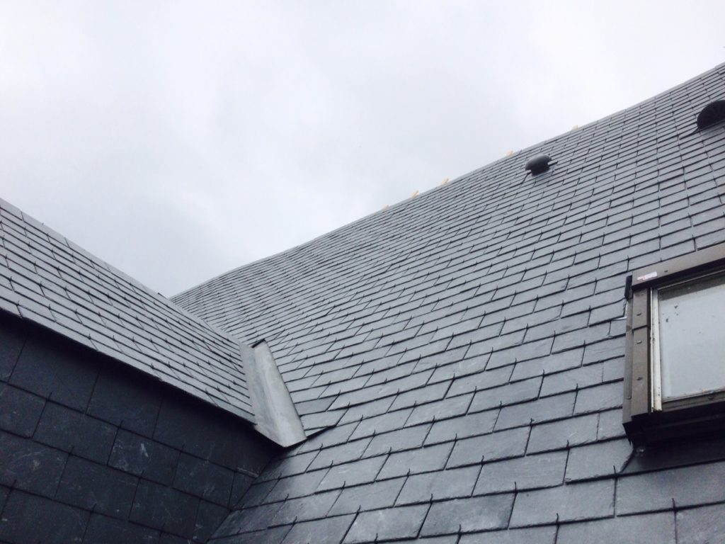 Toiture avec une couverture en ardoise et une fenêtre de toit, réalisée par l’entreprise angevine Charles et Cie